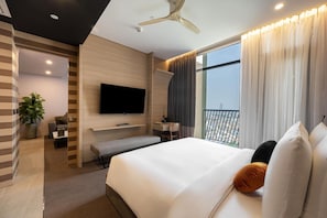 A modern hotel room with a bed, a desk, a TV, and a balcony with curtains. - Sun and Moon Riverside Hotel (Phnom Penh)