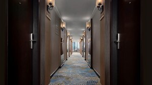 A hotel hallway with a patterned carpet, wooden doors, and wall-mounted lighting fixtures. - Kravan (Phnom Penh)