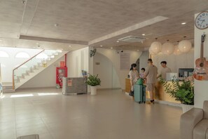 A modern hotel lobby with a reception desk, a staircase, and a large clock on the wall. - The Up Phu Quoc (Phu Quoc)