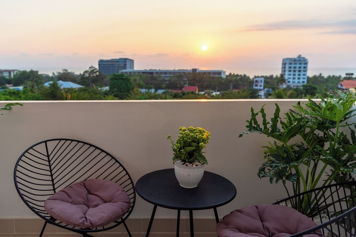 A balcony with two chairs, a small table, and a potted plant.