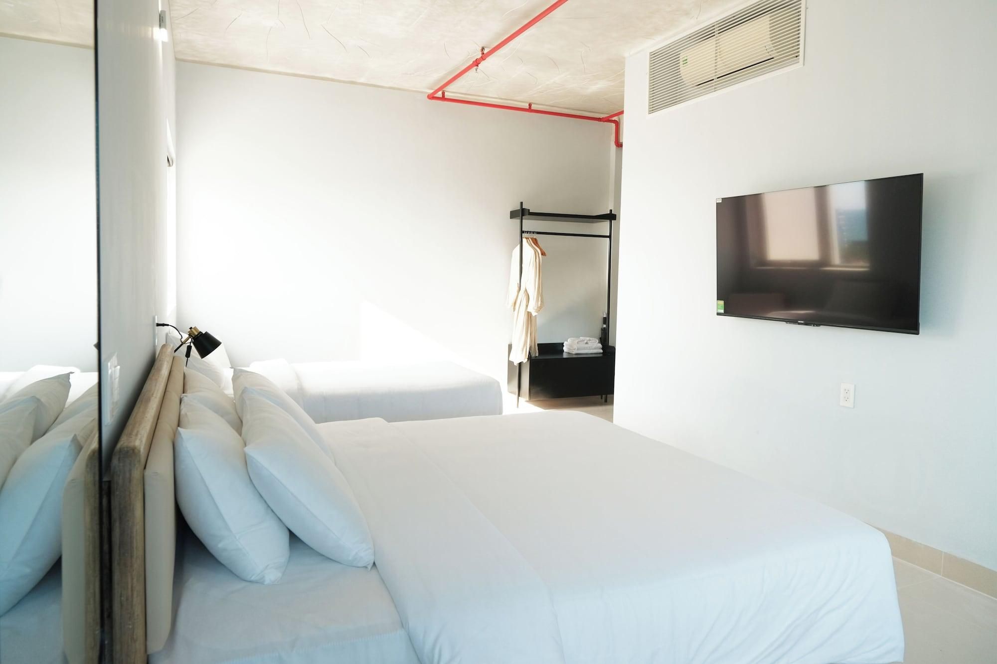 Habitación de hotel con cama, televisión, armario y zona de ducha.