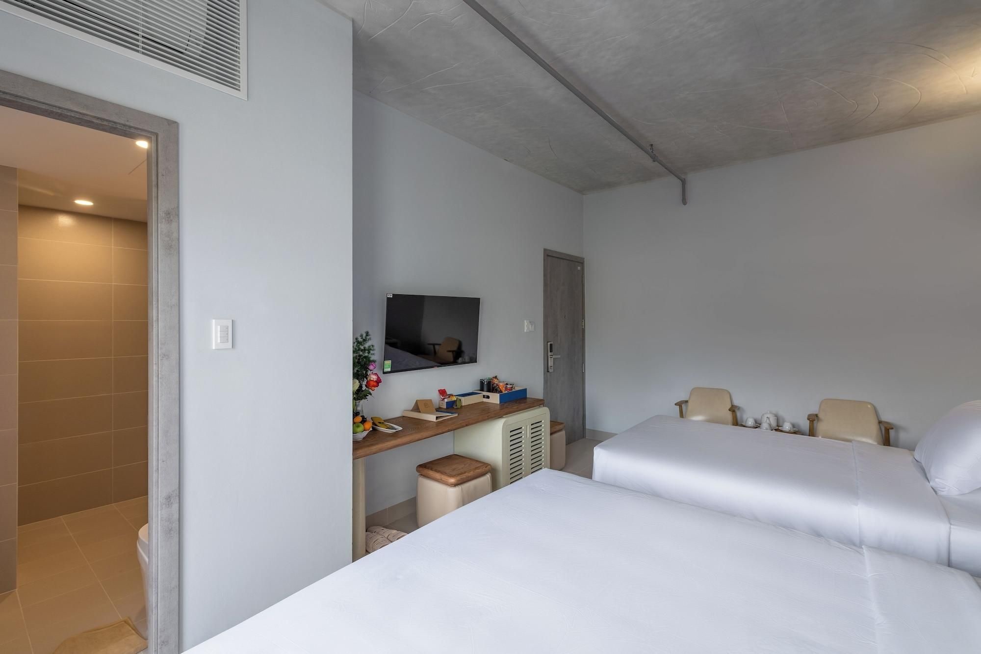 Una habitación de hotel con una cama, un escritorio con ordenador, televisor y puerta.