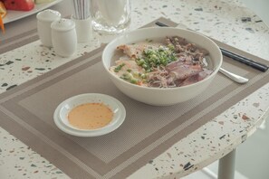 A bowl of soup with meat and vegetables, a small bowl of sauce, salt and pepper shakers, and chopsticks on a table. - The Up Phu Quoc (Phu Quoc)