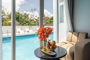 Blick über den Pool mit Esstisch, Blumen in einer Vase und Obstschale.
