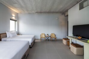 A hotel room with two beds, a TV, a small table with chairs, and a desk with a computer. - The Up Phu Quoc (Phu Quoc)