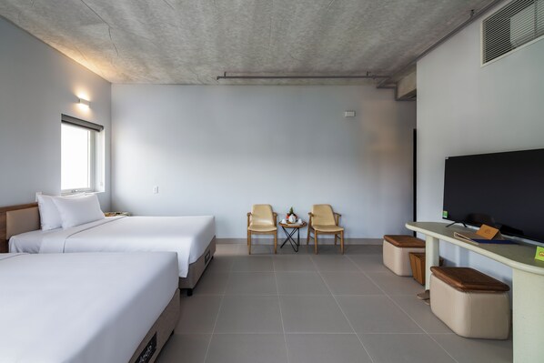 A hotel room with two beds, a TV, a small table with chairs, and a desk with a computer. - The Up Phu Quoc (Phu Quoc)