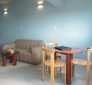 Un salon avec un canapé, une table ronde en bois et deux chaises.