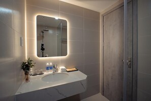 A modern bathroom with a large mirror, a marble sink, and a shower. - The Up Phu Quoc (Phu Quoc)