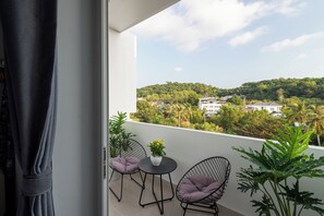 A balcony with two chairs, a table, and a potted plant. - The Up Phu Quoc (Phu Quoc)