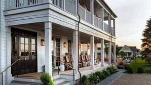 A two-story house with a covered porch, a front door, and a small front yard with plants. - Baron's Cove (Sag Harbor)