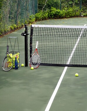 A tennis court with a net, two tennis rackets, and a basket of tennis balls. - Baron's Cove (Sag Harbor)