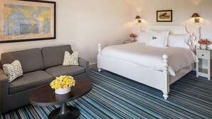 A hotel room with a bed, a sofa, a coffee table, and a world map on the wall. - Baron's Cove (Sag Harbor)