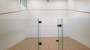 A squash court with glass doors, wooden flooring, and a red line marking the playing area. - Sporthotel Papenburg (Papenburg)