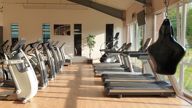 A gym with multiple treadmills and stationary bikes arranged in rows. - Sporthotel Papenburg (Papenburg)