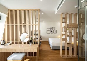 Ein modernes Hotelzimmer mit einem Holztisch, einem Bett und einer Glastrennwand.