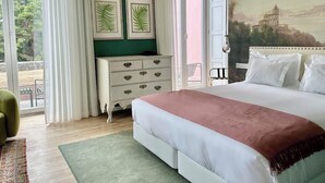 A bedroom with a bed, a dresser, a green wall, and a painting of a building. - Solar dos Cantos Botanic House and Garden (Ponta Delgada)