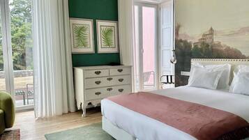 A bedroom with a bed, a dresser, a green wall, and a painting of a building.