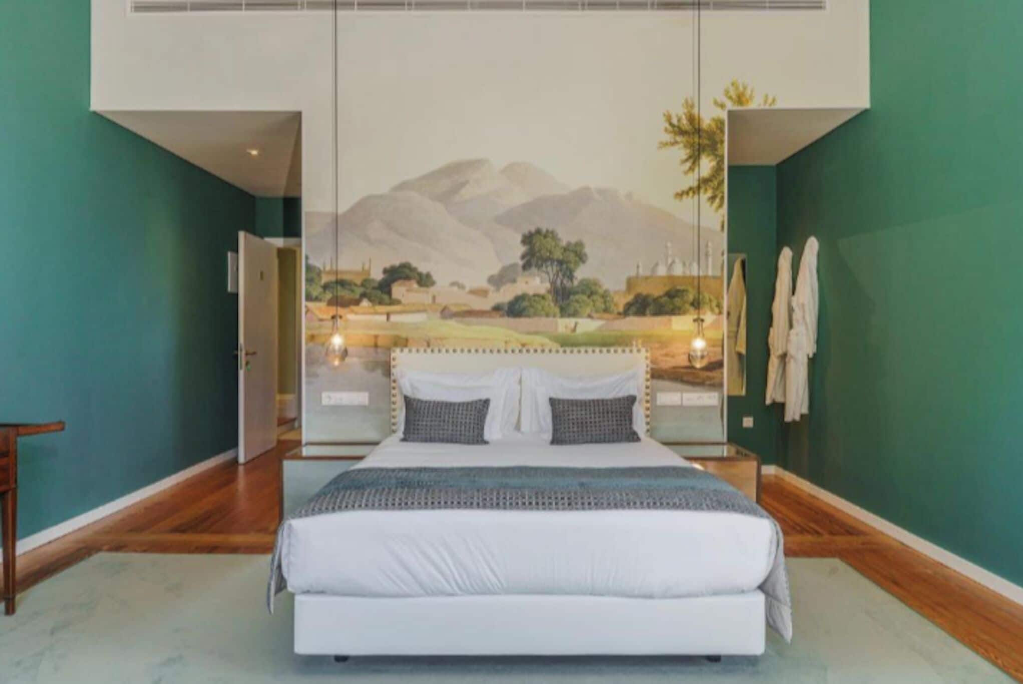 A bedroom with a large bed, a mural on the wall, and a view of the outdoors.