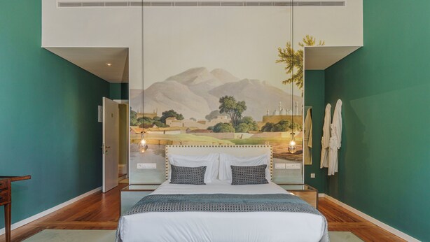 A bedroom with a large bed, a mural on the wall, and a view of mountains. - Solar dos Cantos Botanic House and Garden (Ponta Delgada)