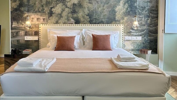 A large bed with a white headboard, two pillows, and a beige blanket. - Solar dos Cantos Botanic House and Garden (Ponta Delgada)
