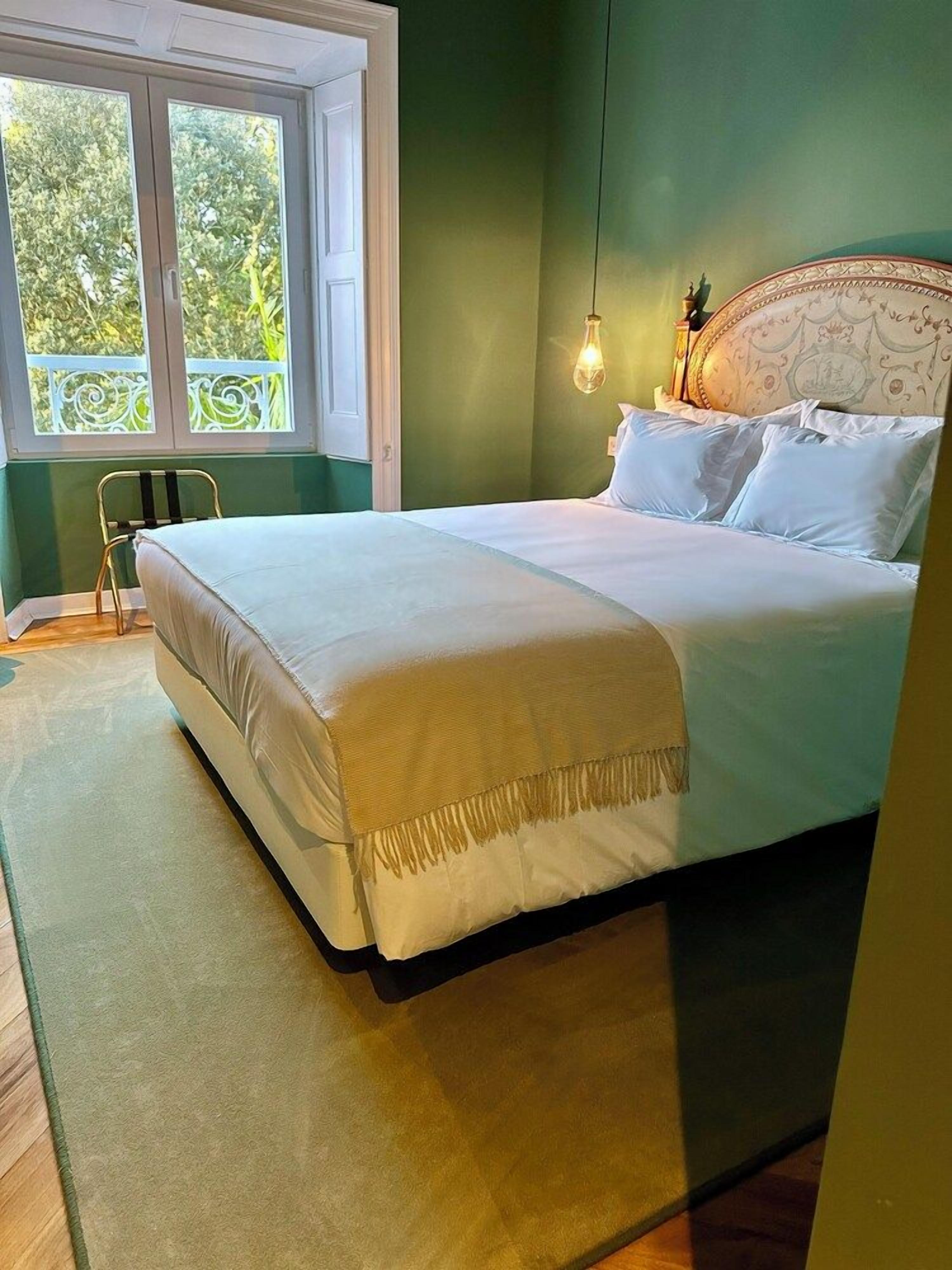 A bedroom with a bed, a window, and a hanging light fixture.