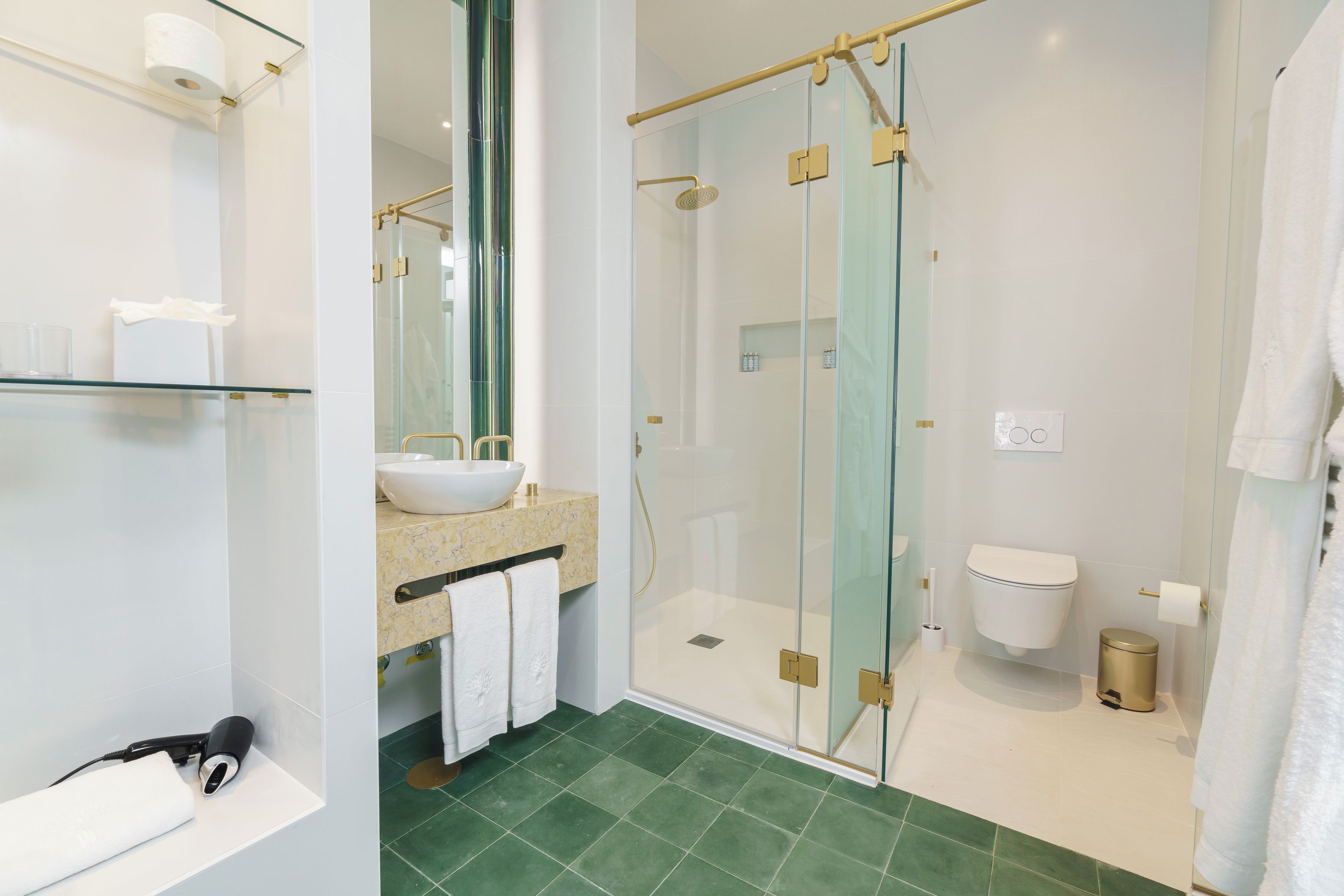 Un baño moderno con ducha envuelta en vidrio, un lavabo blanco y un inodoro.