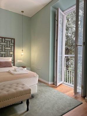 A bedroom with a bed, a nightstand, a hanging light, and a view of the outdoors through a glass door. - Solar dos Cantos Botanic House and Garden (Ponta Delgada)