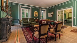 A spacious living room with a large sofa, two armchairs, and a coffee table. There is a fireplace and a large mirror on the wall. - Solar dos Cantos Botanic House and Garden (Ponta Delgada)