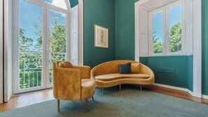 A room with a curved sofa, a single armchair, and a framed picture on the wall. - Solar dos Cantos Botanic House and Garden (Ponta Delgada)