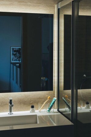 Un baño moderno con un espejo grande, un lavamanos y cepillos de dientes sobre la encimera.