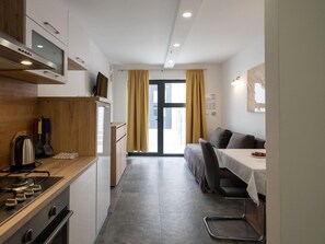 A compact kitchen with a stove, microwave, and wooden cabinets. A dining area with a table and chairs is visible in the background. - D-elegant Lapad Dubrovnik (Dubrovnik)