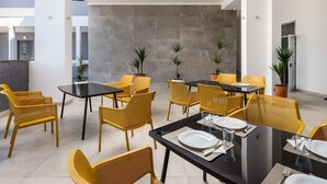 A modern dining area with yellow chairs and black tables, featuring a grey tiled wall and potted plants. - D-elegant Lapad Dubrovnik (Dubrovnik)