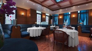 A restaurant with round tables, blue cushioned seating, and a wooden ceiling with a skylight. - Hotel Z Palace and Congress Center (Xanthi)