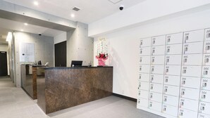A hotel reception area with a marble counter, a wall of lockers, and a security camera. - Lightning Hotel (Tokyo)