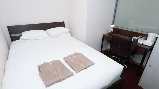 A neatly made bed with white linens, a brown headboard, and two folded towels on the bed. - Lightning Hotel (Tokyo)