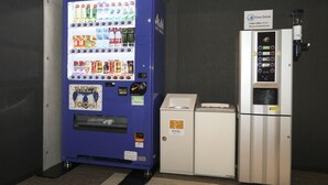 A vending machine with various drinks and snacks, a small refrigerator, and a coffee machine. - Lightning Hotel (Tokyo)