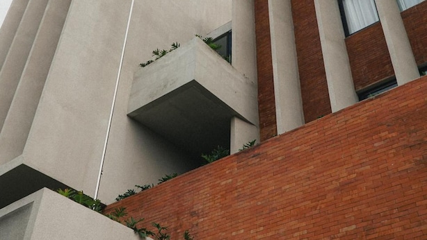 Ein modernes Gebäude mit einer Betonfassade, Ziegelakzenten und einer Fahnenstange.