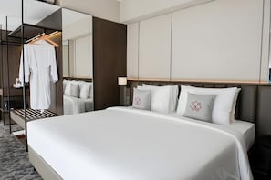 Habitación de hotel con una cama grande, un espejo, un armario y una bata colgada.