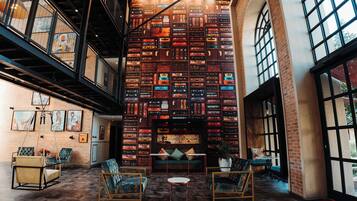 A spacious interior with a high ceiling, exposed brick walls, and a central seating area with a sofa and chairs.