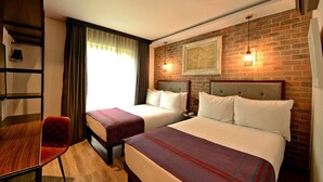 A hotel room with two beds, a desk, a chair, and a brick wall with a framed picture. - Hotel Perte Montecasino (Johannesburg)