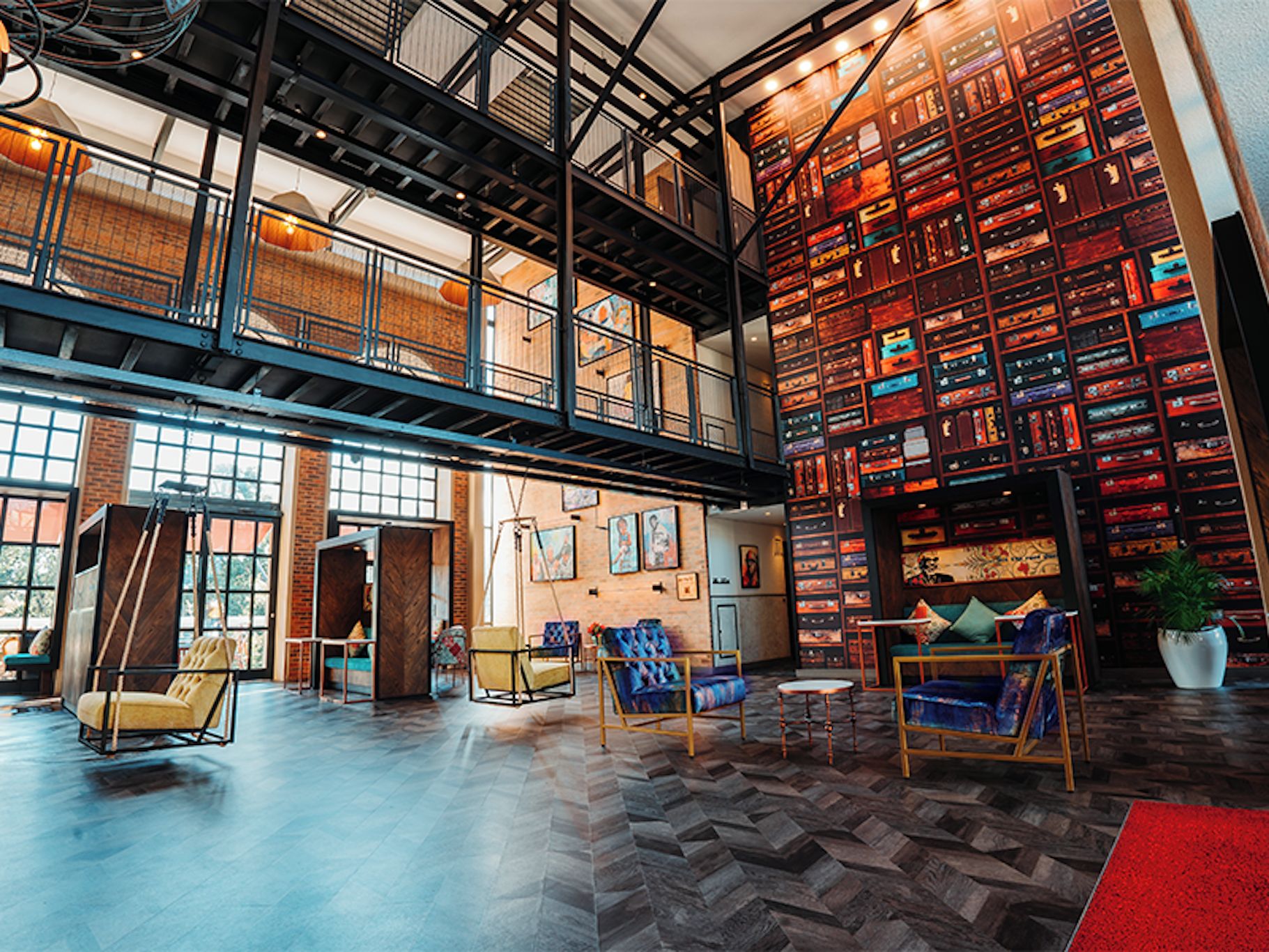 A spacious lobby with a high ceiling, exposed brick walls, and a mezzanine level.