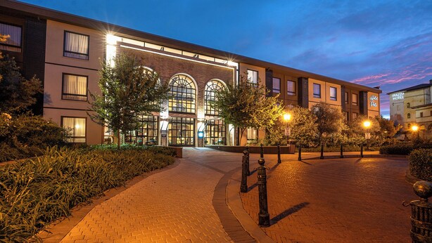 A hotel with a brick facade, large arched windows, and a paved walkway.