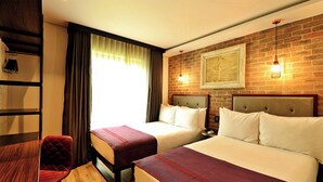 A hotel room with two beds, a wooden desk, a chair, and a brick wall with a framed picture. - Hotel Perte Montecasino (Johannesburg)