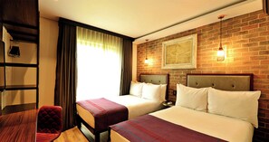 A hotel room with two beds, a wooden desk, a chair, and a brick wall with a framed picture. - Hotel Perte Montecasino (Johannesburg)