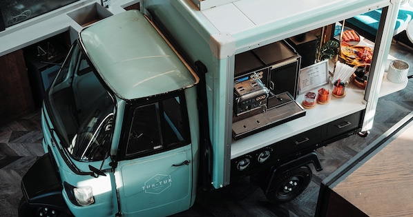 Un bar móvil con diseño vintage, una cafetera y un panel con la carta.
