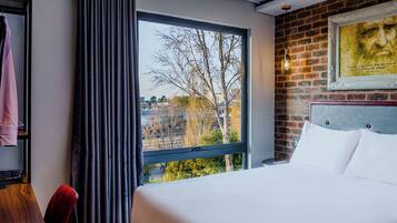 Hotellihuone, jossa on suuri ikkuna, sänky, vaatekaappi ja tiiliseinä.