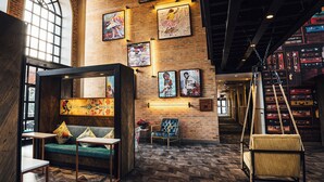 A spacious lounge area with a brick wall, a sofa, a chair, and a hanging swing. - Hotel Perte Montecasino (Johannesburg)