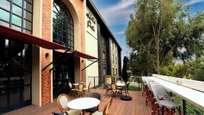 A hotel patio with outdoor seating, a brick facade, and large windows.
