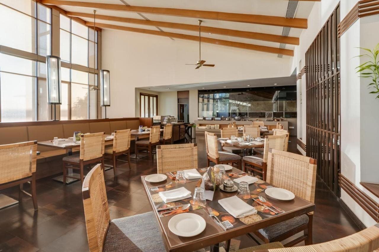 A spacious dining area with high ceilings, large windows, and modern furnishings.