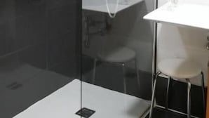 Een moderne badkamer met een douchecabine van glas, een wit wastafelmeubel en een spiegel.